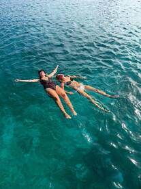 Two friends enjoy a refreshing swim in crystal-clear waters, perfect for a fun day out on the boat.