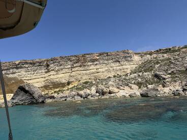 A stunning view of rocky cliffs and clear turquoise waters, showcasing the natural beauty of the coastline — perfect for exploring by boat.