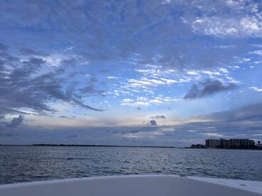 A serene view from the bow of a boat, showcasing a beautiful sky and calm waters, perfect for a peaceful day on the water.