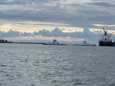 A scenic view of multiple vessels navigating the water, showcasing the maritime activity in the harbor under a cloudy sky.