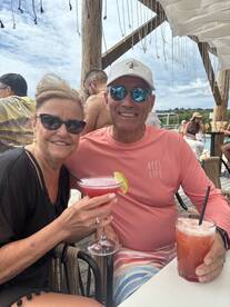A cheerful couple enjoys cocktails at a lively outdoor bar, perfect for celebrating special moments or relaxing with friends.