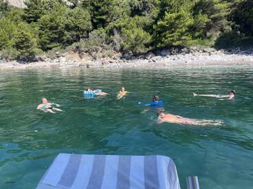 A lively group enjoys a refreshing swim in crystal-clear waters, perfect for snorkeling and beach fun. This scene captures the essence of a relaxing day on the water.