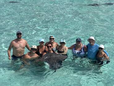 A joyful group interacts with a stingray in shallow waters, creating a memorable wildlife experience perfect for adventure seekers.