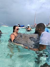 Guests interact with a stingray in shallow turquoise waters, creating a memorable wildlife experience in a tropical setting.
