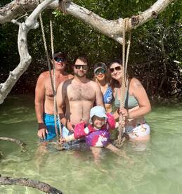 A joyful family enjoys a fun day in the water near mangroves, with a child in floaties, capturing the essence of a memorable aquatic adventure.