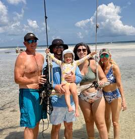 A joyful family poses on the beach, with a child swinging happily in the foreground — a perfect moment of fun and togetherness in a tropical paradise.