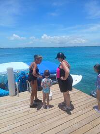 A family enjoys a sunny day by the water, interacting with a child and crew members near a boat — perfect for memorable aquatic adventures.