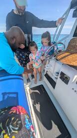 A joyful moment on a boat as two young girls interact with an adult, showcasing family fun and bonding on the water.