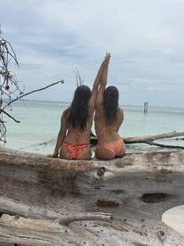 Two friends enjoy a beach day, posing with arms raised against a stunning ocean backdrop — a perfect moment for summer adventures and beach celebrations.