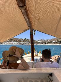 A couple enjoys a relaxing moment on a boat, taking in the scenic views of the coastline — perfect for a leisurely day on the water.