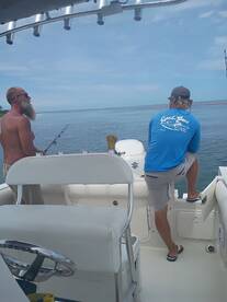 Two friends enjoy a fishing trip on a boat, casting lines into the calm ocean waters — a perfect day for angling and camaraderie.