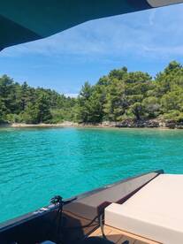 A scenic view from the deck of a boat, showcasing the vibrant turquoise waters and lush greenery of the coastline — perfect for exploring secluded beaches.