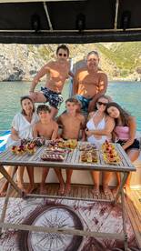 A joyful family gathers on a boat, enjoying a delicious spread of food while celebrating together — perfect for memorable outings on the water.