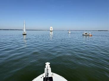 A serene view of multiple boats sailing on calm waters under a clear blue sky, showcasing the beauty of a day on the water.