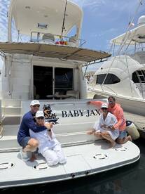 A cheerful group poses on the back of the 'Baby Jax' yacht, celebrating their time on the water — perfect for memorable outings and gatherings.