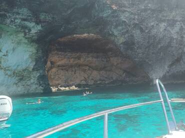 A stunning view of a natural cave with swimmers enjoying the crystal-clear turquoise waters — a perfect spot for exploration and adventure.