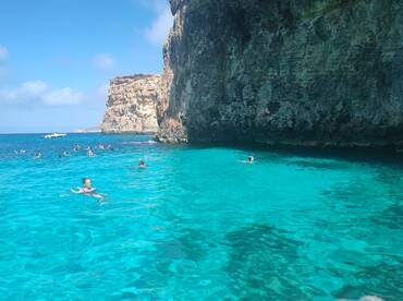 A vibrant scene of swimmers enjoying the crystal-clear waters near a stunning rocky coastline, perfect for snorkeling and group adventures.
