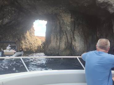 A scenic view of a boat navigating through a natural rock arch, showcasing the beauty of coastal exploration. Perfect for adventure seekers and nature lovers.