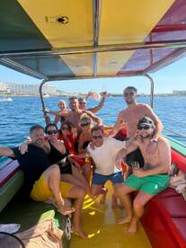 A lively group enjoys a fun day on the water, celebrating with drinks aboard a colorful boat — perfect for memorable outings with friends.