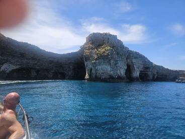 A scenic view of dramatic cliffs and clear blue waters, with a guest enjoying the boat ride — perfect for exploring coastal wonders.