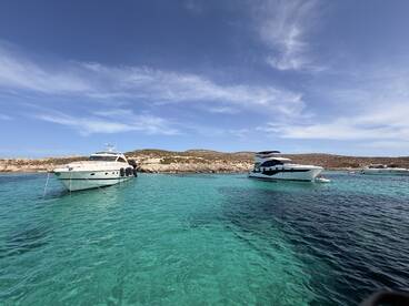 Two luxurious yachts anchored in crystal-clear turquoise waters, showcasing the beauty of a serene boating destination.