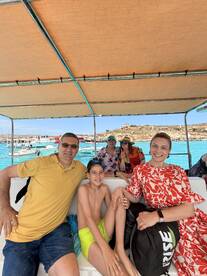 A cheerful family enjoys their time aboard a boat, capturing a fun moment together in the beautiful turquoise waters — perfect for family vacations and memorable outings.