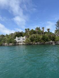 A picturesque view of a historic structure surrounded by lush greenery along the turquoise waters, perfect for exploring scenic landmarks during a boat trip.