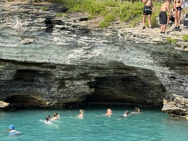 A lively group enjoys swimming in crystal-clear turquoise waters near stunning rock formations, perfect for adventurous outings and exploration.