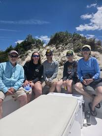 A cheerful group enjoys a day on the boat, with a scenic beach backdrop — perfect for family outings and adventures on the water.