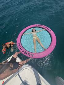 A relaxing scene featuring friends enjoying a sunny day on the water, with one person lounging on a floating mat while others swim nearby — perfect for summer fun and aquatic adventures.
