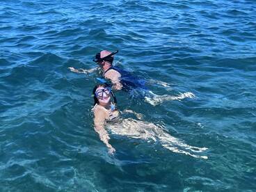 Two snorkelers enjoy a vibrant underwater adventure, showcasing the beauty of marine life while swimming in crystal-clear waters.