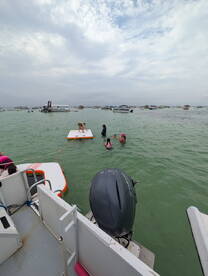 A lively scene with children and adults enjoying water activities around a floating mat, showcasing the fun and excitement of a day on the water.