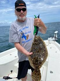 An enthusiastic angler proudly displays a freshly caught flounder while fishing on a boat — a perfect moment for fishing enthusiasts and adventure seekers.