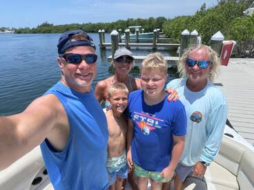 A cheerful family poses for a selfie on a boat at the dock, capturing a memorable moment before their aquatic adventure.
