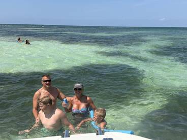 A joyful family enjoys a sunny day swimming in clear waters, creating unforgettable memories together in a tropical paradise.