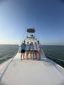 A cheerful group poses on the bow of a boat, enjoying a beautiful day on the water — perfect for memorable outings and celebrations.