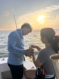 A young boy and a woman share a moment while fishing at sunset, showcasing the joy of ocean adventures and family bonding.
