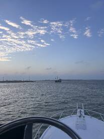 A scenic view from the bow of a boat, showcasing a distant ship against a beautiful sky — perfect for maritime adventures and sightseeing.