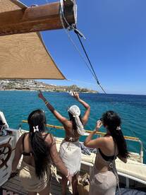 A lively group of friends enjoys a sunny day on a boat, celebrating and taking in the beautiful ocean views — perfect for summer adventures and memorable outings.