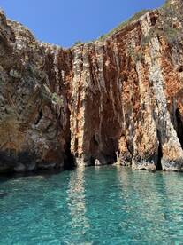 A stunning view of rocky cliffs reflecting in the clear turquoise waters, showcasing the natural beauty of the coastline — perfect for eco tours and scenic boat trips.