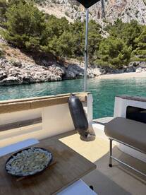 A beautifully arranged plate of snacks on a boat, set against a serene backdrop of rocky shores and clear waters, perfect for enjoying a meal while cruising.