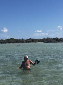 A man enjoys a refreshing swim in shallow waters, showcasing the beauty of a beachside experience — perfect for island adventures.