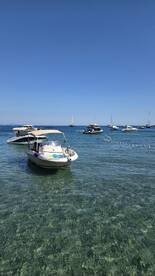 A scenic view of boats anchored in crystal-clear waters, with guests enjoying their time on the water — perfect for a day of relaxation and exploration.