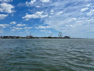 A picturesque view of a vibrant coastline featuring a ferris wheel and various attractions, perfect for capturing the essence of a fun day on the water.