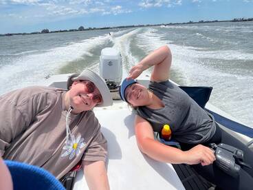 Two friends enjoy a sunny day on the water, capturing fun moments while boating — perfect for creating lasting memories on the sea.