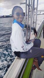 A woman enjoys her time on a boat, capturing the moment with her phone while surrounded by the beautiful ocean scenery.