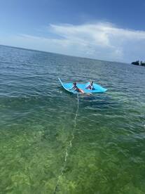 Two children enjoy a fun day on a floating mat in clear waters, perfect for summer adventures and family outings.