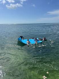 A lively group enjoys a fun day on a floating mat in the clear waters, perfect for family outings and summer adventures.