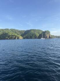 A picturesque view of a sailboat navigating through tranquil waters, surrounded by lush green islands — a perfect representation of coastal beauty and adventure.