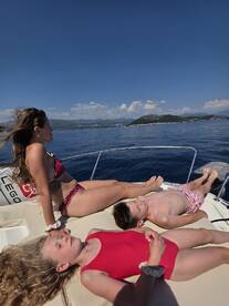 A family enjoys a sunny day on the boat, relaxing and sunbathing under clear blue skies — a perfect summer getaway on the water.